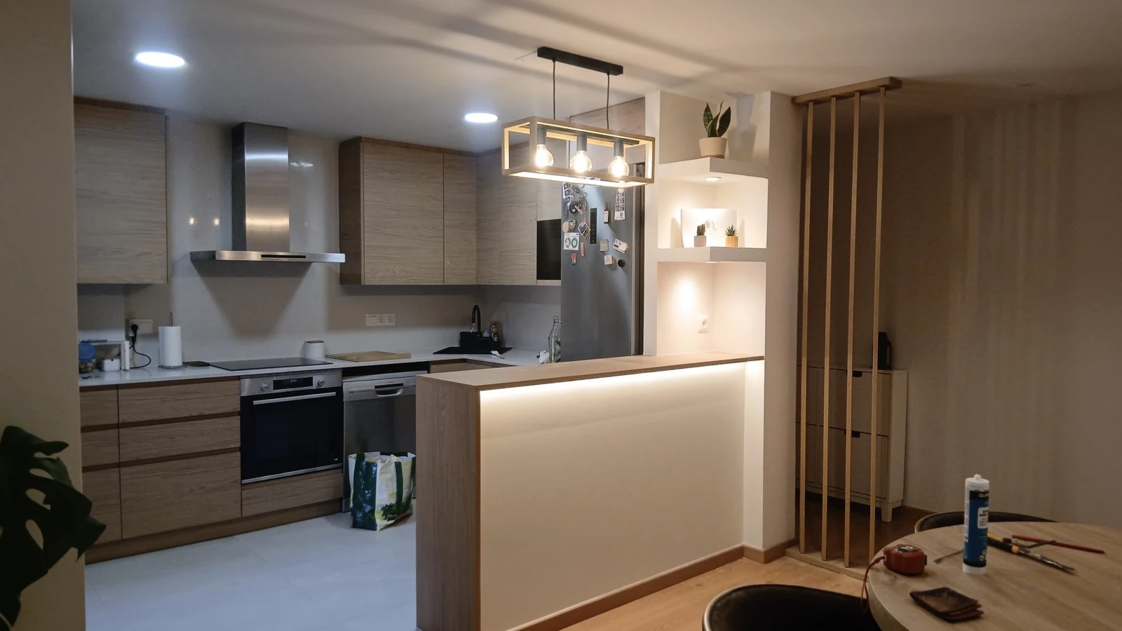 Cocina reformada por Bricomanitas con barra iluminada y listones de madera