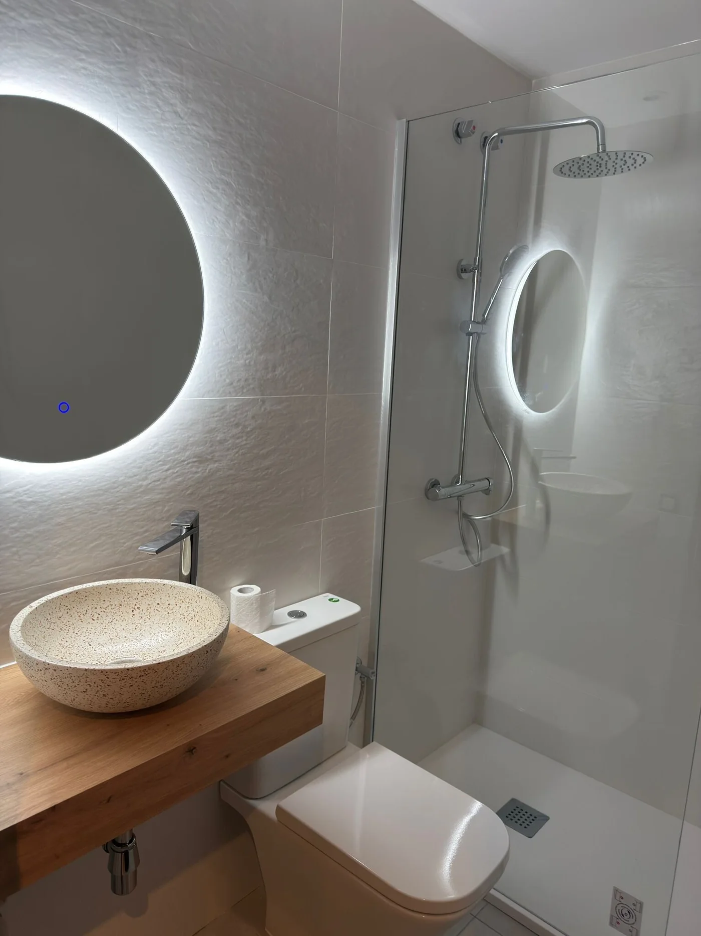 Baño con lavabo sobre encimera y revestimientos claros